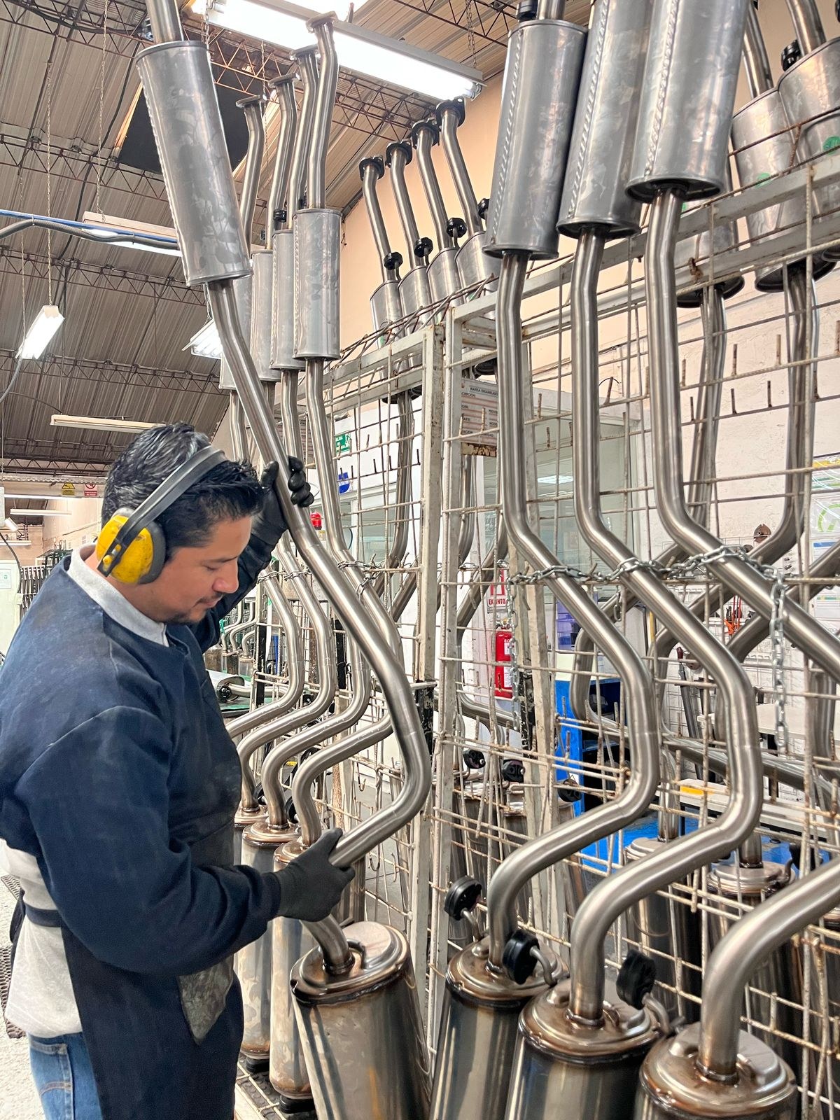 Operario organizando sistemas de escape en la línea de producción